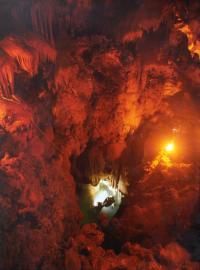 David Goldie at the surface in Ana Nurau(view from above). The dry cave is illuminated by candle light and the diver is silhouetted by an underwater flash.